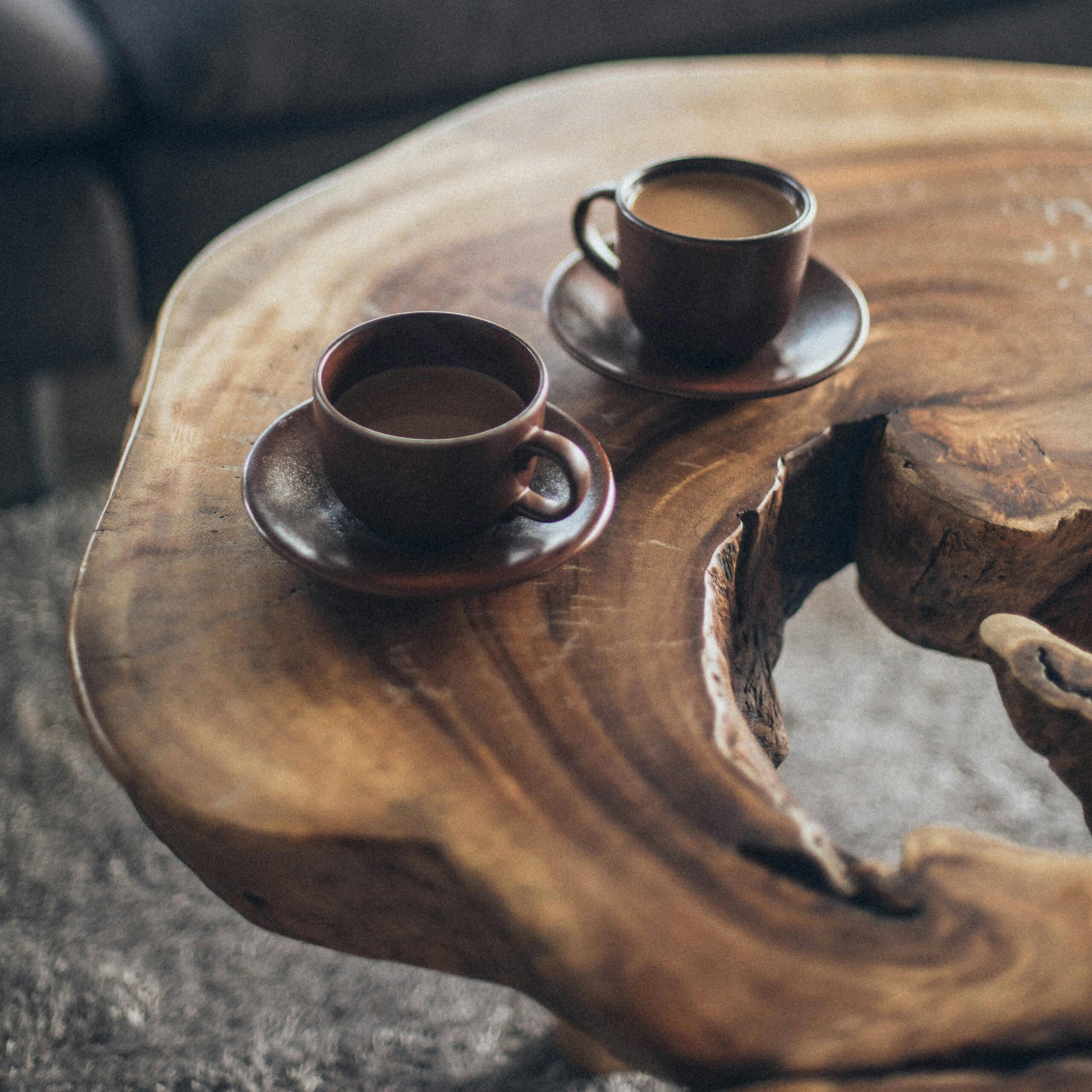 Two coffee cups on a rustic wooden table create a warm, inviting atmosphere.